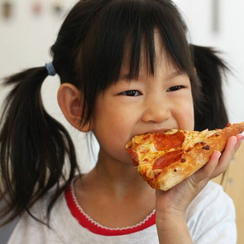 Young girl in white shirt eating pizza